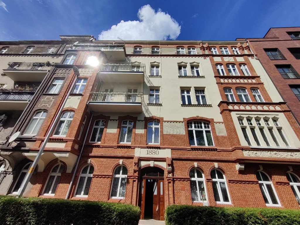 Renowacja kamienicy we Wrocławiu — elewacja frontowa z czerwonej cegły i jasnego tynku, napis 1880 nad wejściem